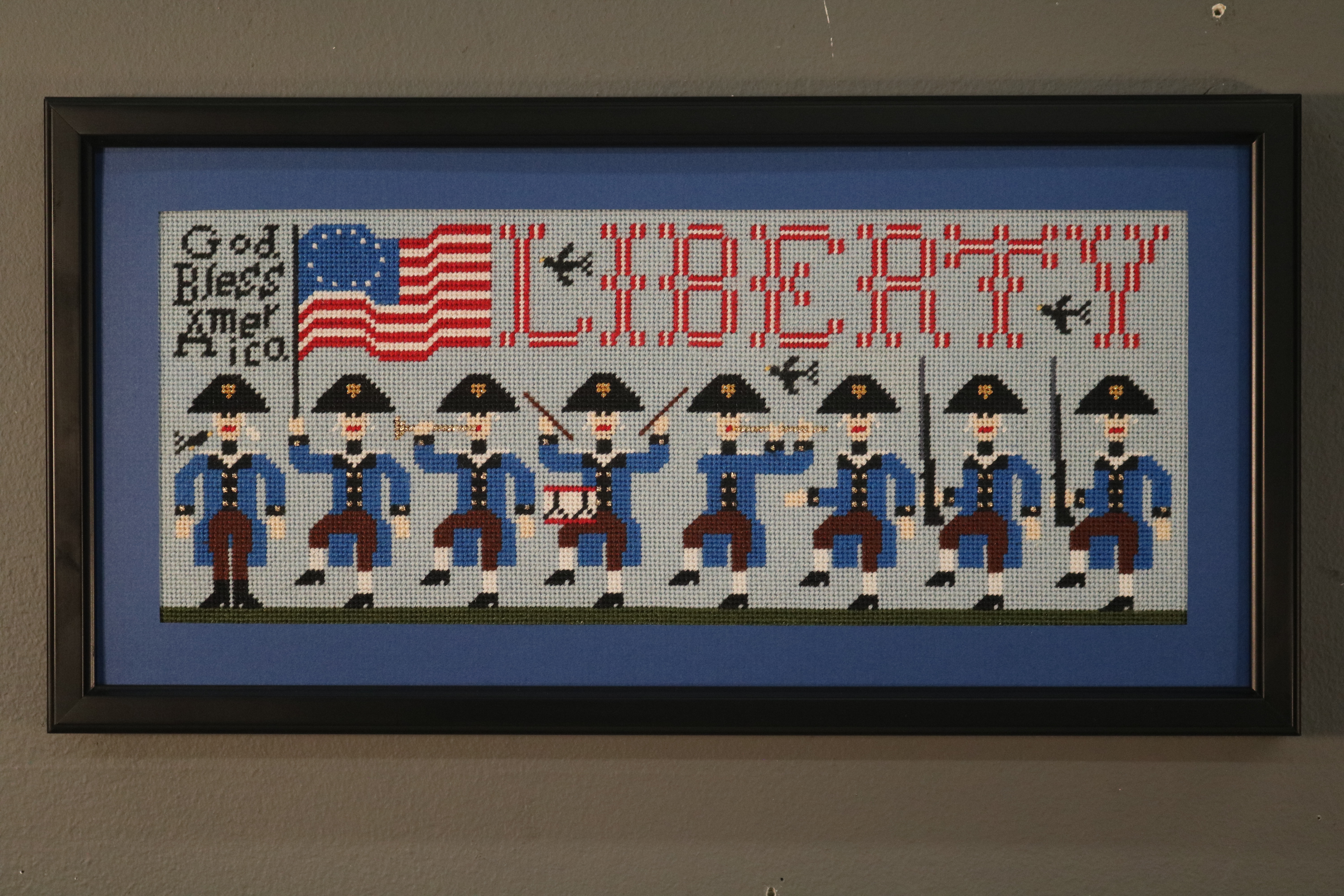 Framed cross stitch with soldiers and the word Liberty